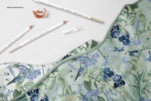 Botanical-themed jersey fabric mockup shown from a top view, with marking pencils and a pencil shaving nearby.