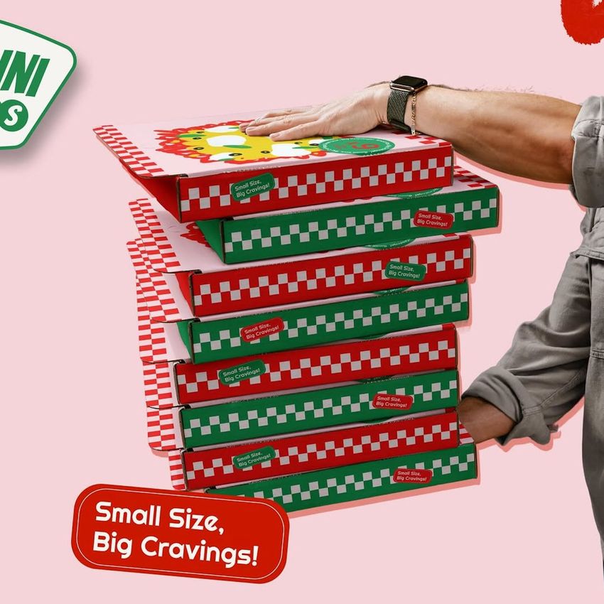 Stack of six pizza box mockups with red and green checkerboard patterns, a hand resting on the top box, and a pink background.