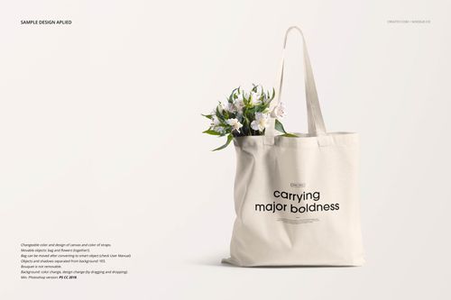 Front view of a cream-colored tote bag mockup with black text, holding white flowers, on a light background.
