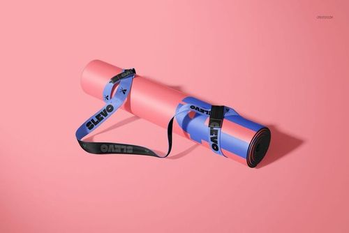 Rolled oval yoga mat mockup featuring pink and blue tones, black strap, and angled front view on pink surface.