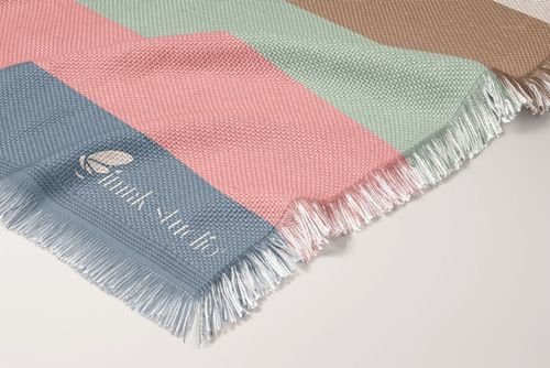 Woven polyester coverlet mockup featuring pastel geometric stripes and fringed edges, shown in a close-up view.