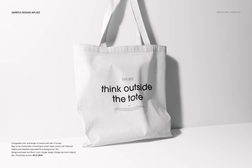 Front view of a plain white tote bag mockup with centered black lettering, set on a neutral background with soft lighting.