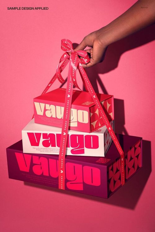 Hand holding three stacked magnetic boxes tied with a ribbon, shown on a pink background, packaging mockup.