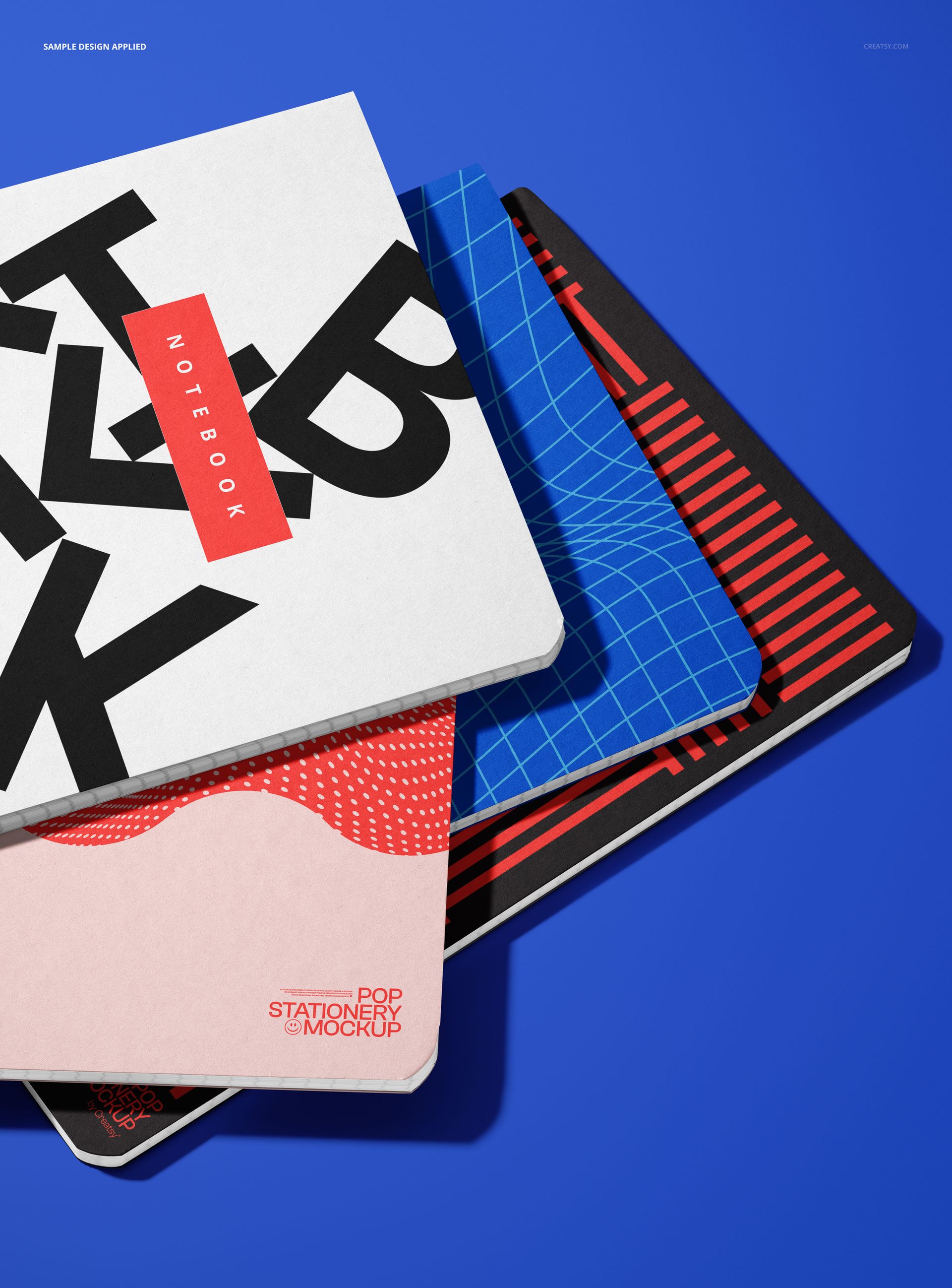 PSD mockup showing four stationery notebooks with varied cover designs, layered diagonally against a vibrant blue backdrop.