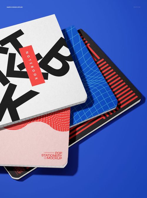 PSD mockup showing four stationery notebooks with varied cover designs, layered diagonally against a vibrant blue backdrop.