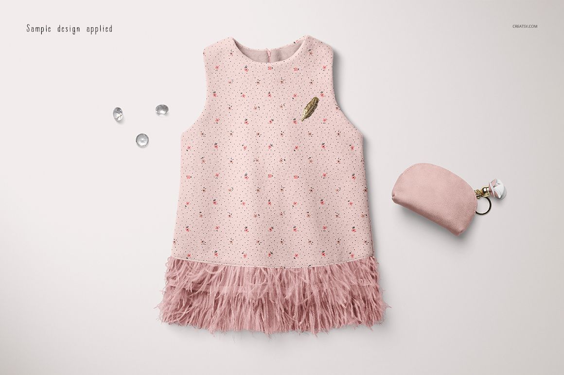 Sleeveless baby dress mockup in soft pink with small scattered patterns and feathered hem, top view on white background.
