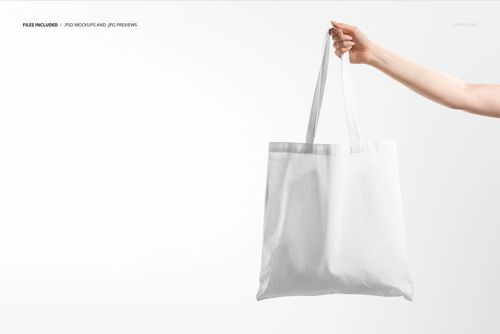 Minimalist white tote bag mockup displayed in a person's hand, set against a bright, uncluttered background.