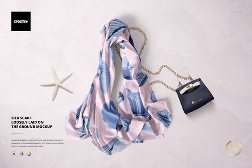 PSD mockup showing a chiffon silk scarf with soft pastel leaf motifs, arranged on a pale textured background with props.