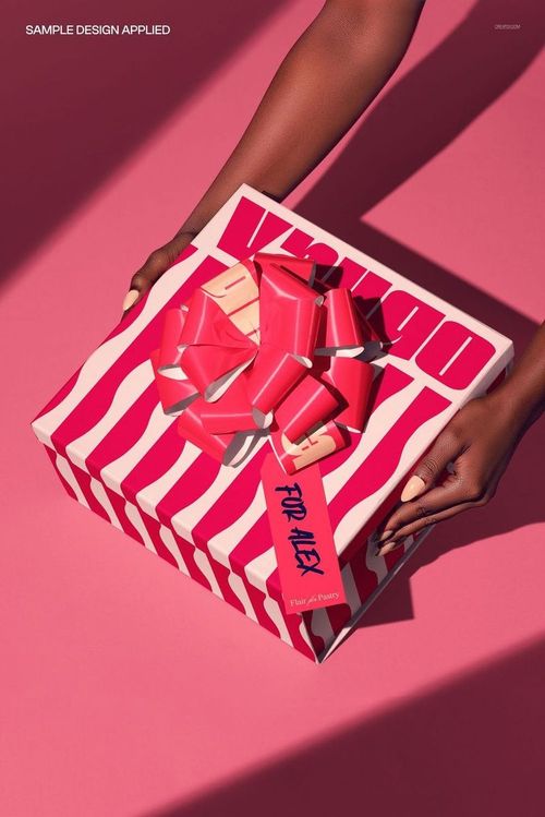 PSD mockup showing a gift box with vivid pink and white wavy stripes, topped with a red bow, held by hands.