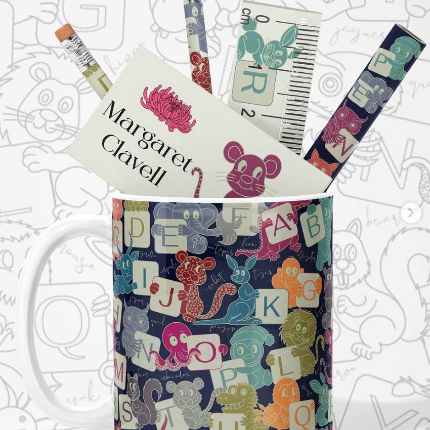 Mug mockup featuring colorful animal alphabet illustrations, filled with stationery items like pencils, ruler, and business card.