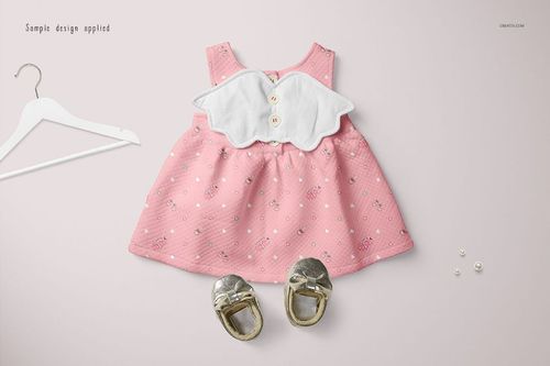 Baby dress mockup featuring a sleeveless pink dress with white collar, gold shoes, hanger, and pearls on a pale surface.