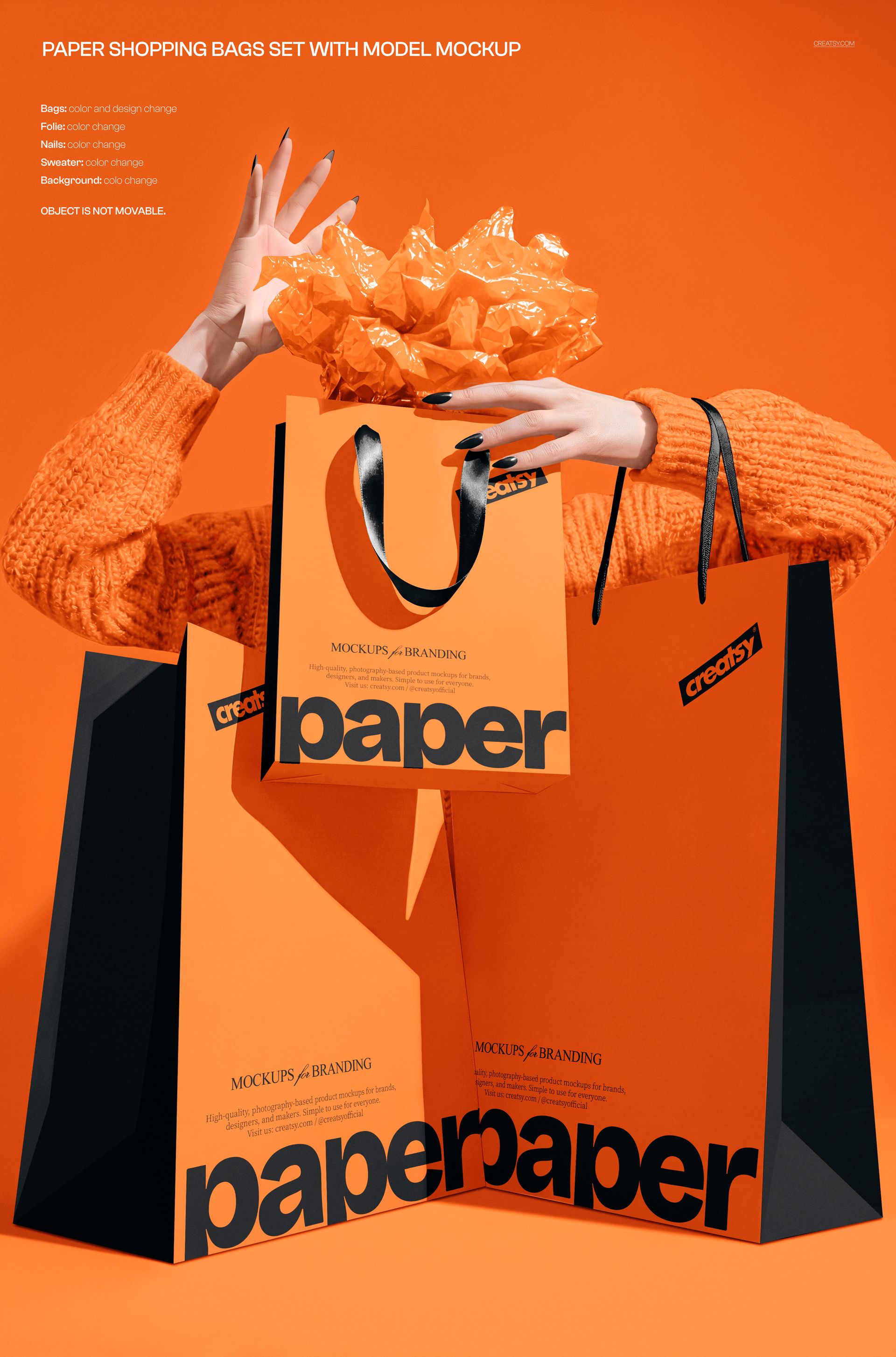 PSD mockup featuring orange paper shopping bags with black handles, shown with hands and orange props in a studio setting.