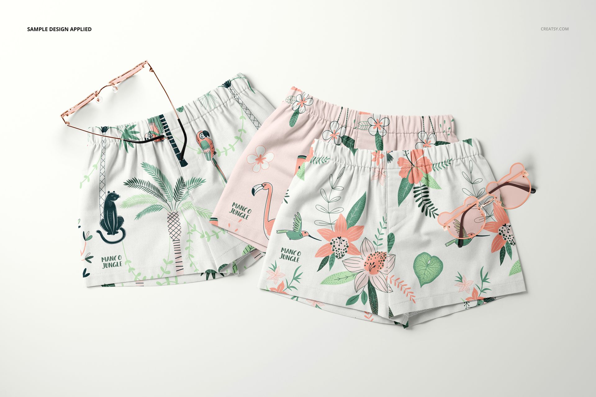 PSD mockup featuring two baby and kids shorts with pastel tropical prints, shown from above alongside two pairs of sunglasses.