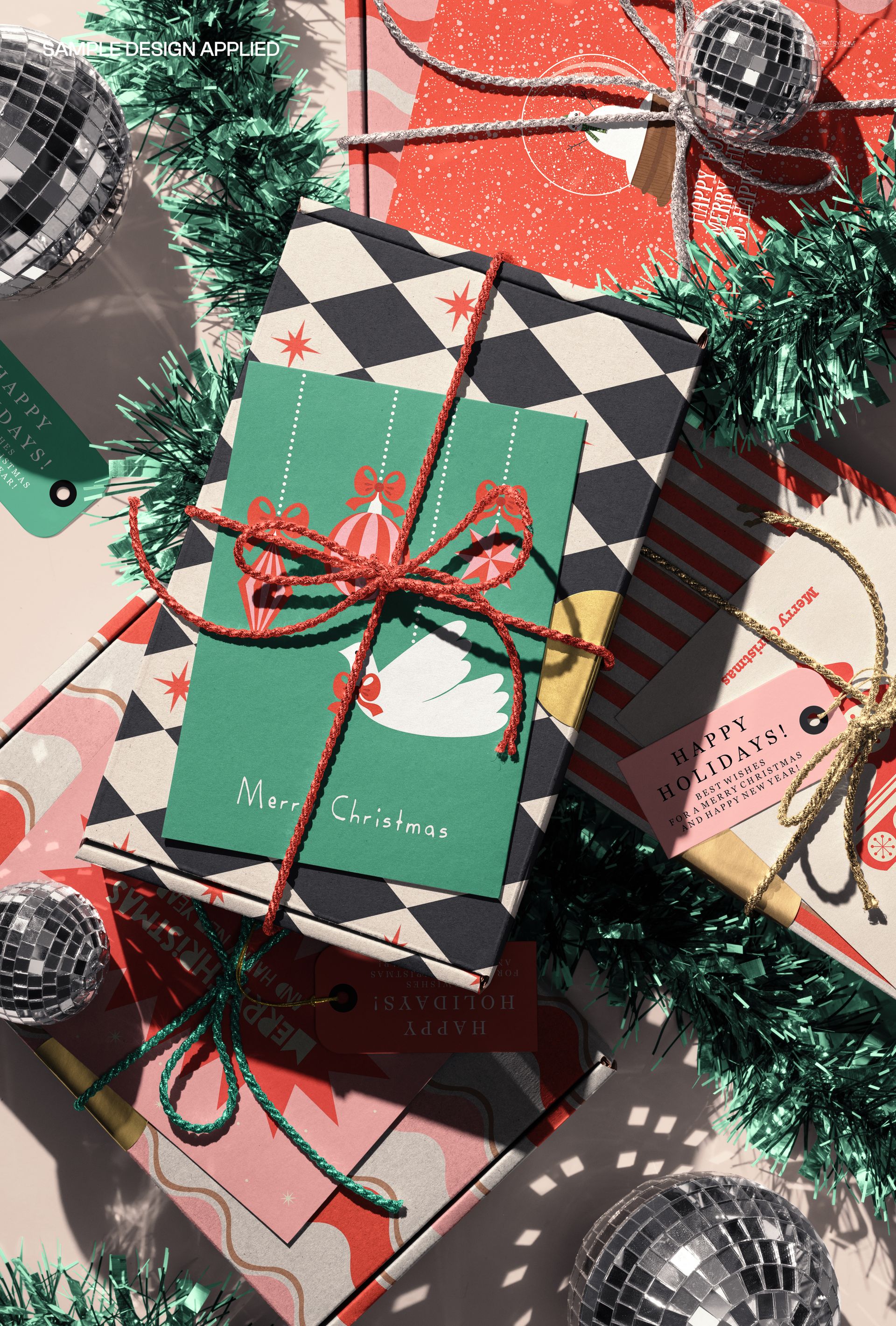 Christmas-themed PSD mockup showing kraft gift boxes, decorative cards, disco balls, and green garland from above.