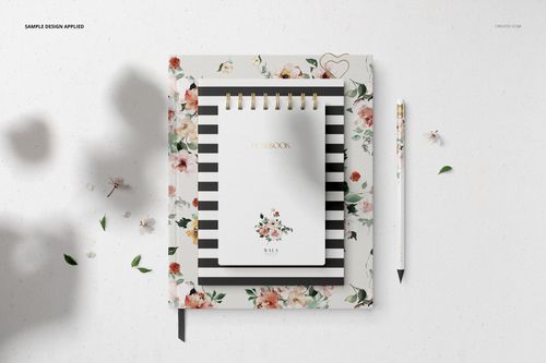 Stationery set mockup featuring a spiral notebook, hardcover book, and pen with floral and striped designs, top view.