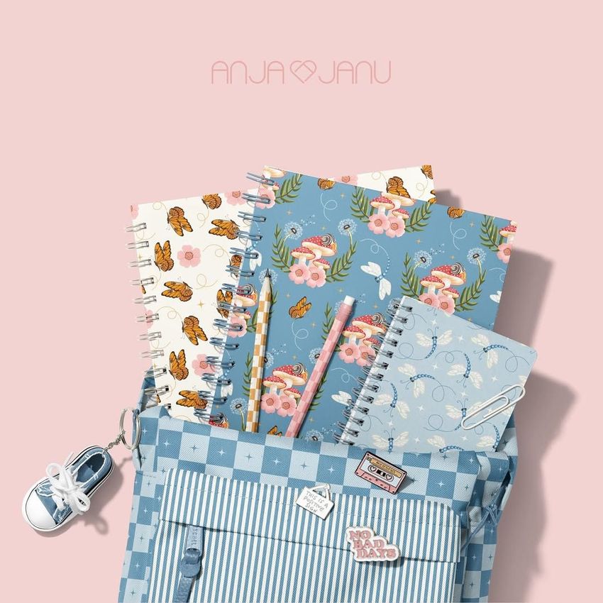School backpack mockup with blue checkered pocket, holding spiral notebooks with floral and mushroom patterns, and pastel pencils.