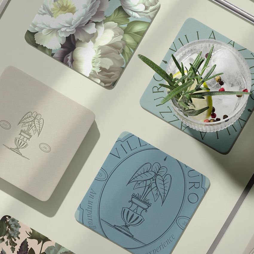 Square coasters mockup featuring various designs laid out on a light surface, with a cocktail glass and green garnish on one coaster.