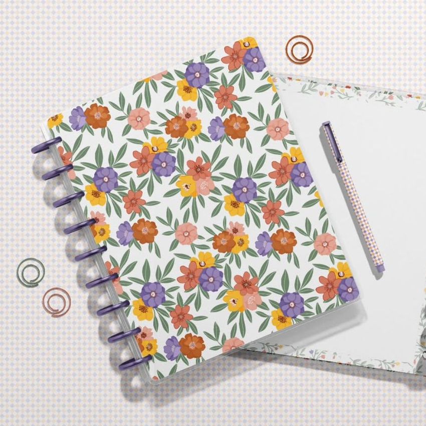 Floral spiral planner mockup, with one planner closed and another open on a checkered surface, pen and paper clips nearby.
