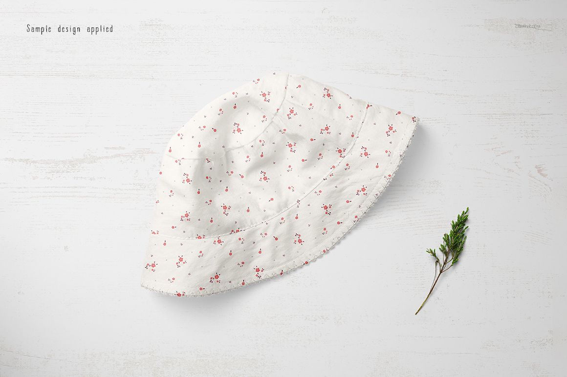 Baby hat mockup featuring a white fabric with delicate pink flowers, displayed on a pale textured background.
