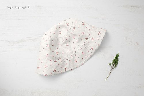Baby hat mockup featuring a white fabric with delicate pink flowers, displayed on a pale textured background.