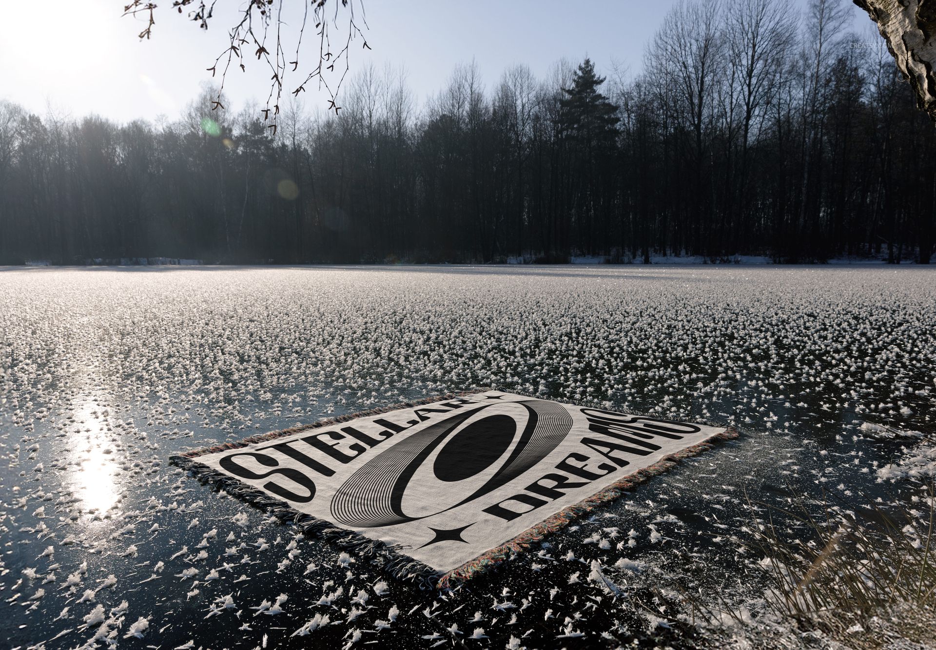 Winter-themed jacquard blanket mockup featuring geometric design, laid flat on icy lake with trees in background.