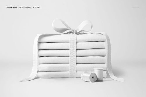 PSD mockup showing neatly stacked white fabrics tied with a ribbon, with sewing threads arranged in the foreground.