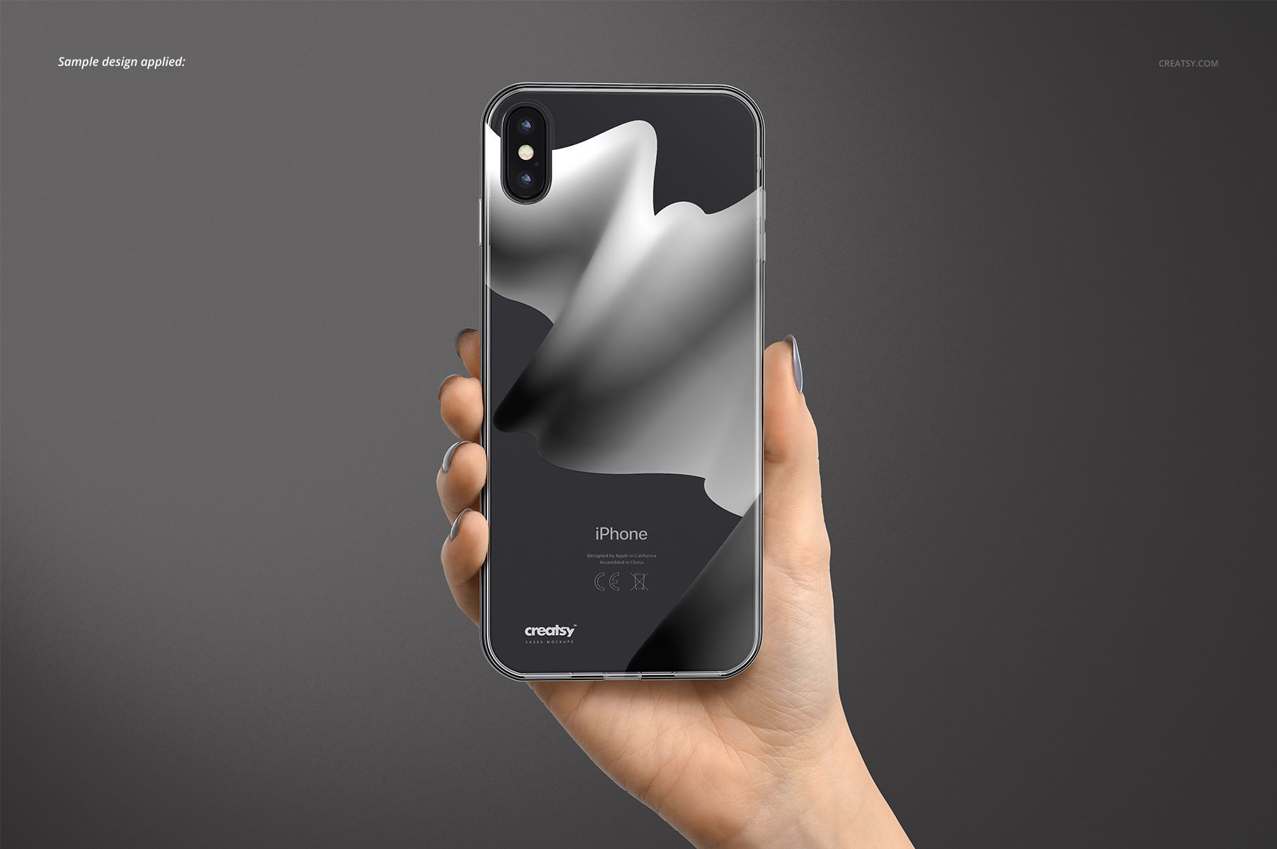 Hand holding an iPhone XS Max with a transparent case displaying a monochrome abstract pattern, mockup on gray backdrop.