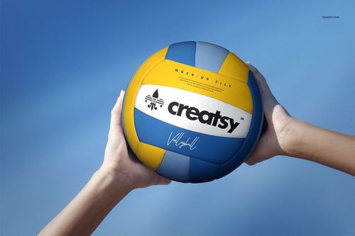 Close-up view of a volleyball ball mockup featuring blue, yellow, and white segments held by two hands outdoors.