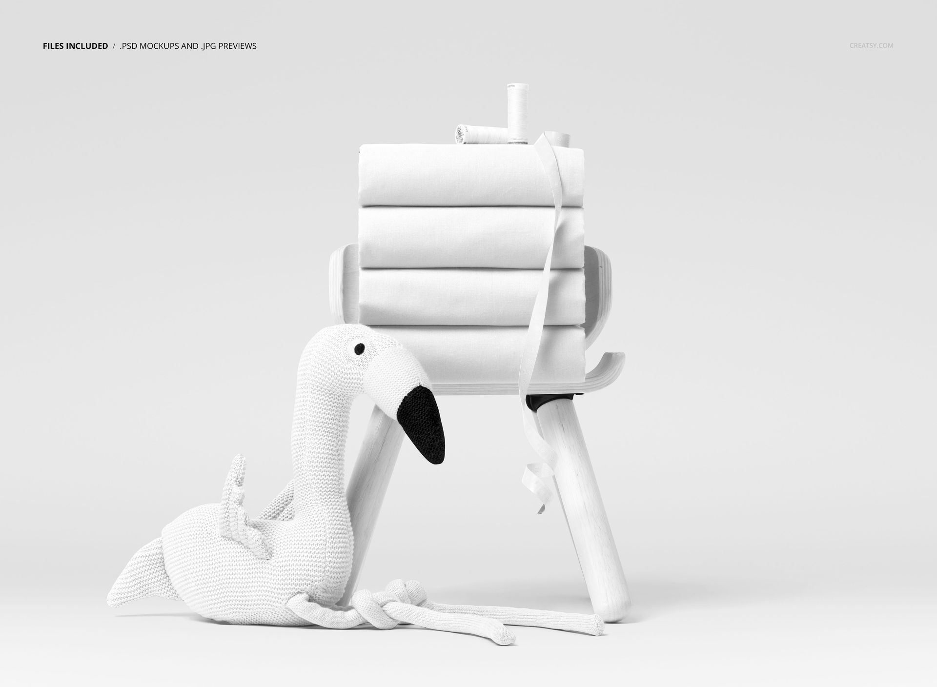 Front view of a mockup showing several neatly folded fabrics on a stool, accompanied by a textured flamingo plush.