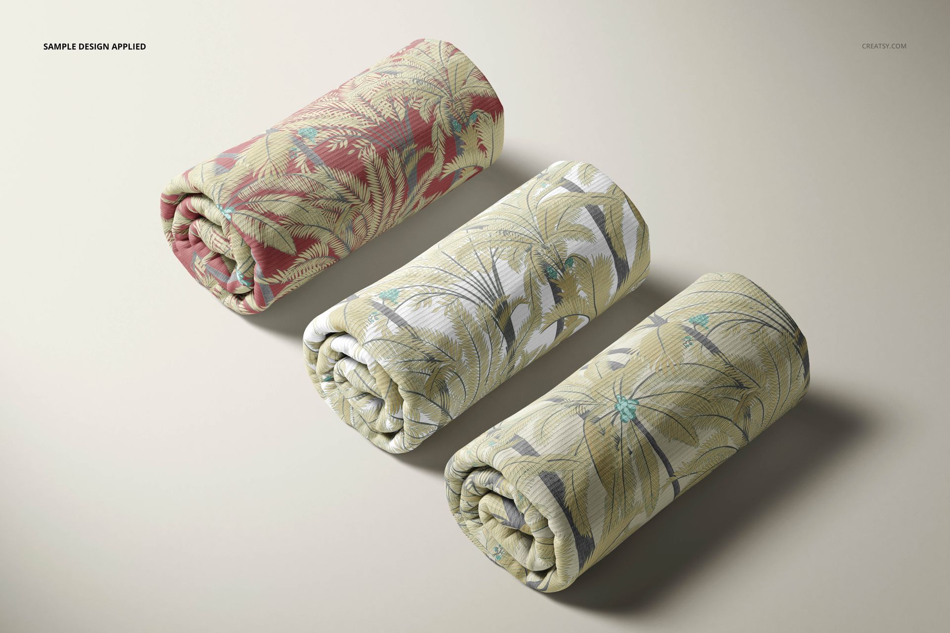 Three rolled rib knit fabric pieces with tropical leaf patterns in red, green, and beige tones on a neutral surface.