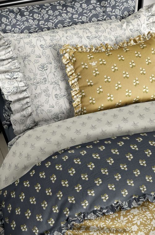 PSD mockup of bedding set with ruffled pillows and duvet covers in coordinating floral prints and soft colors.