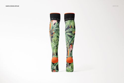 Front view of knee high socks mockup with tropical leaf and flamingo pattern, black cuffs, and orange heels on a light background.