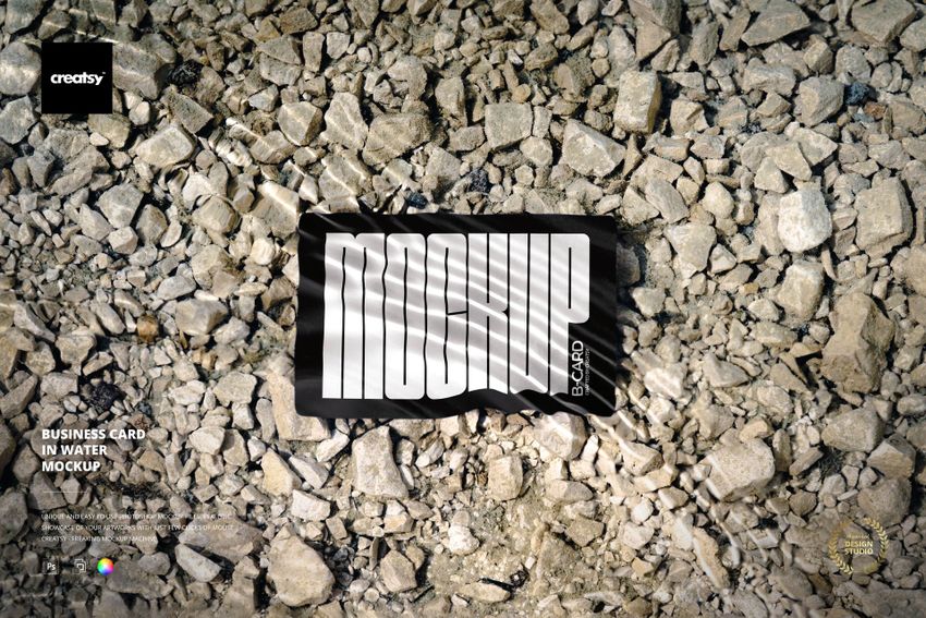Rectangular business card mockup partially submerged in water, resting on a surface covered with light gray stones.