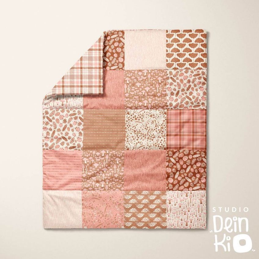 Baby patchwork quilt mockup featuring a folded corner, with various autumn-themed patterns in warm pink and brown tones on a light background.