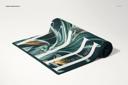 Rolled beach towel mockup with a tropical leaf pattern in green, orange, and white, displayed on a plain surface.
