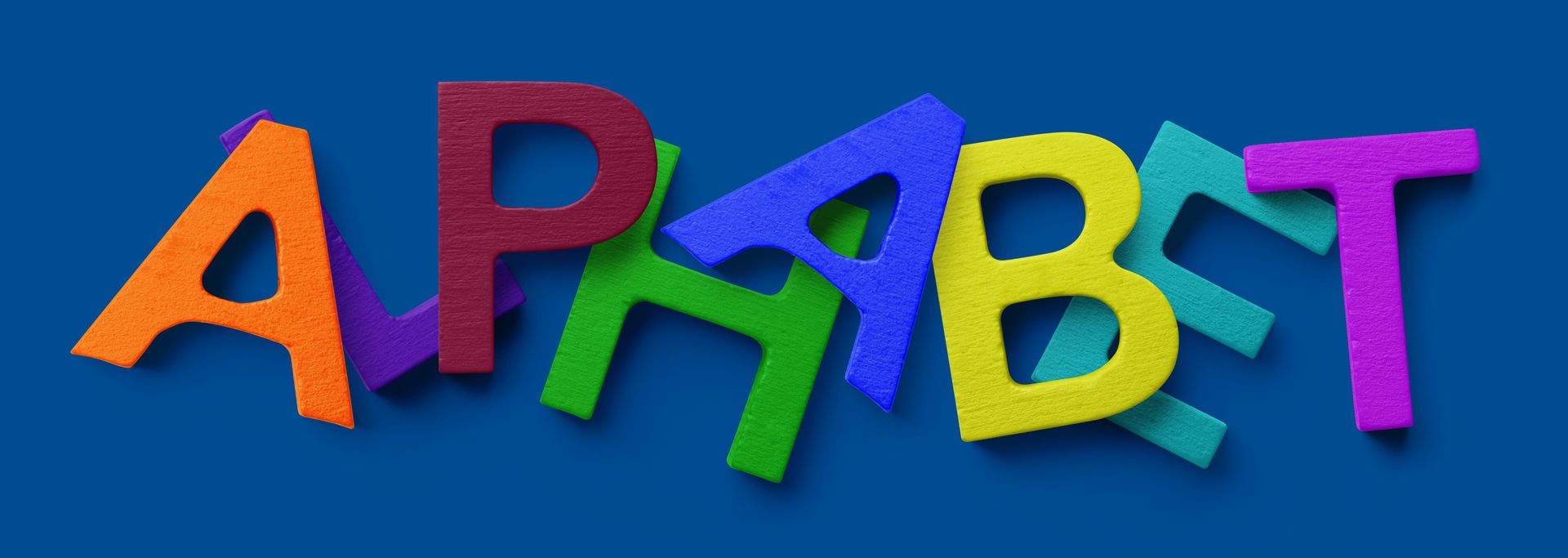 PSD mockup showing vibrant painted wooden letters forming the word 'ALPHABET' against a blue surface.