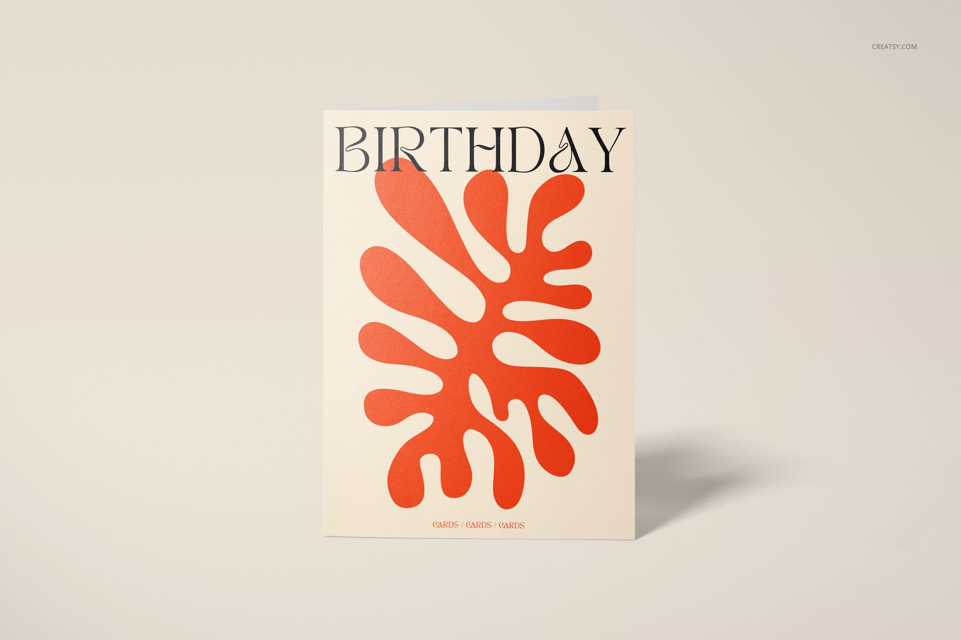 Front view of a 5x7 greeting card mockup standing upright on a light beige surface, featuring bold orange abstract shapes.