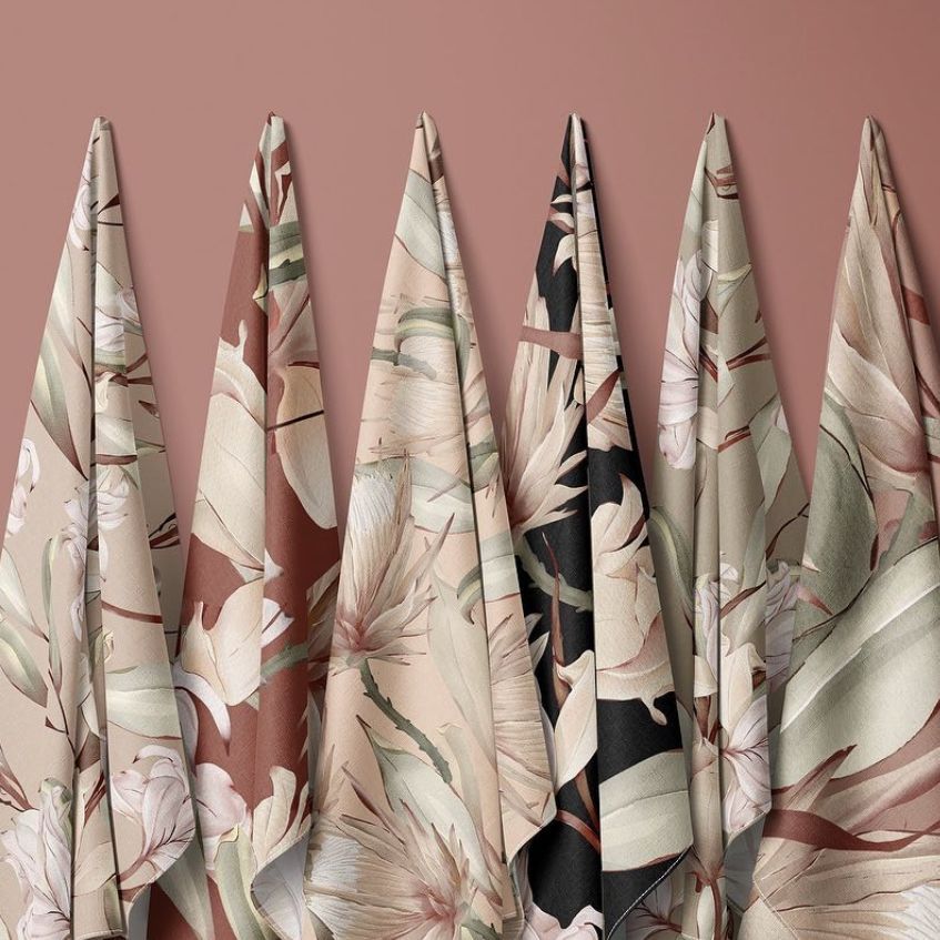 Hanging fabrics mockup featuring five cloth panels with floral patterns in muted pink, beige, and black tones against a pink wall.