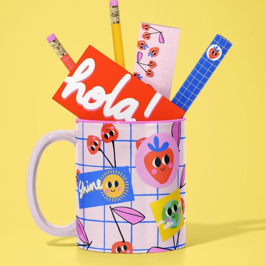 Mug mockup with a colorful grid and cherry pattern, holding pencils, a ruler, and a bright card with bold text on a yellow background.
