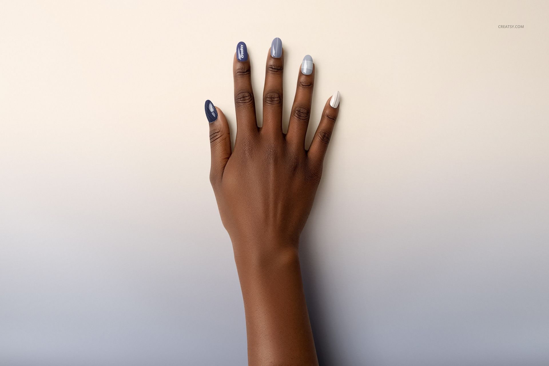 Top view of a hand with five nails painted in different colors, displayed on a soft gradient surface for nail mockup.