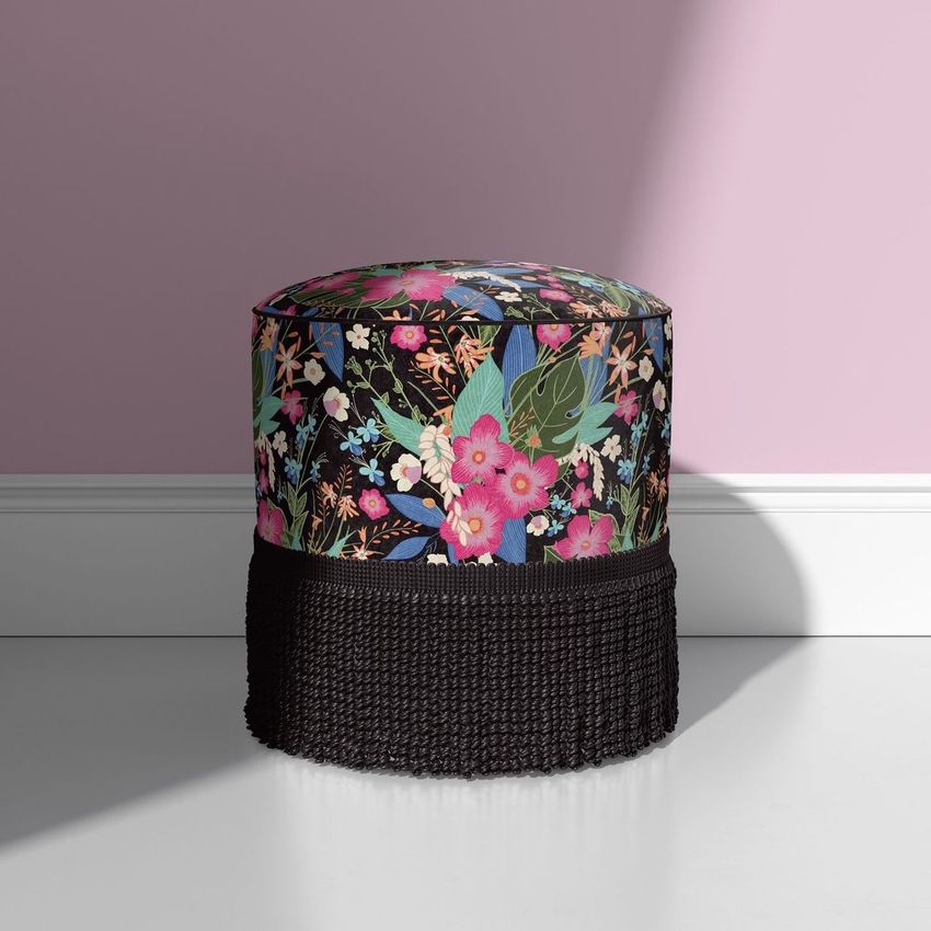 Fringed velvet footstool mockup featuring a colorful botanical print with pink and green flowers against a light pink wall.