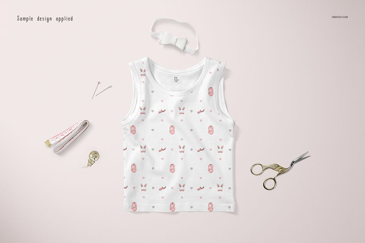 White baby tank top mockup displayed flat with soft pink designs, shown with scissors, tape measure, and sewing pins.