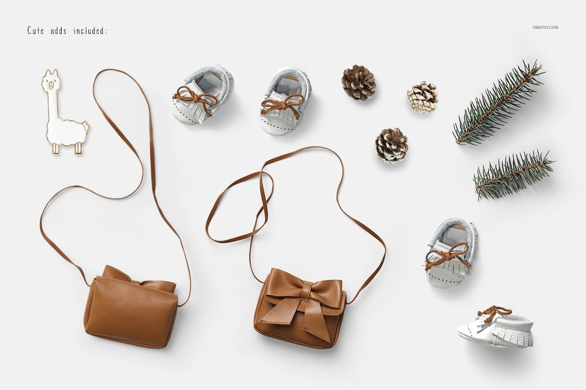Flat lay of baby dress mockup set featuring brown bags with bow detail, baby shoes, pine cones, and fir branch on white background.