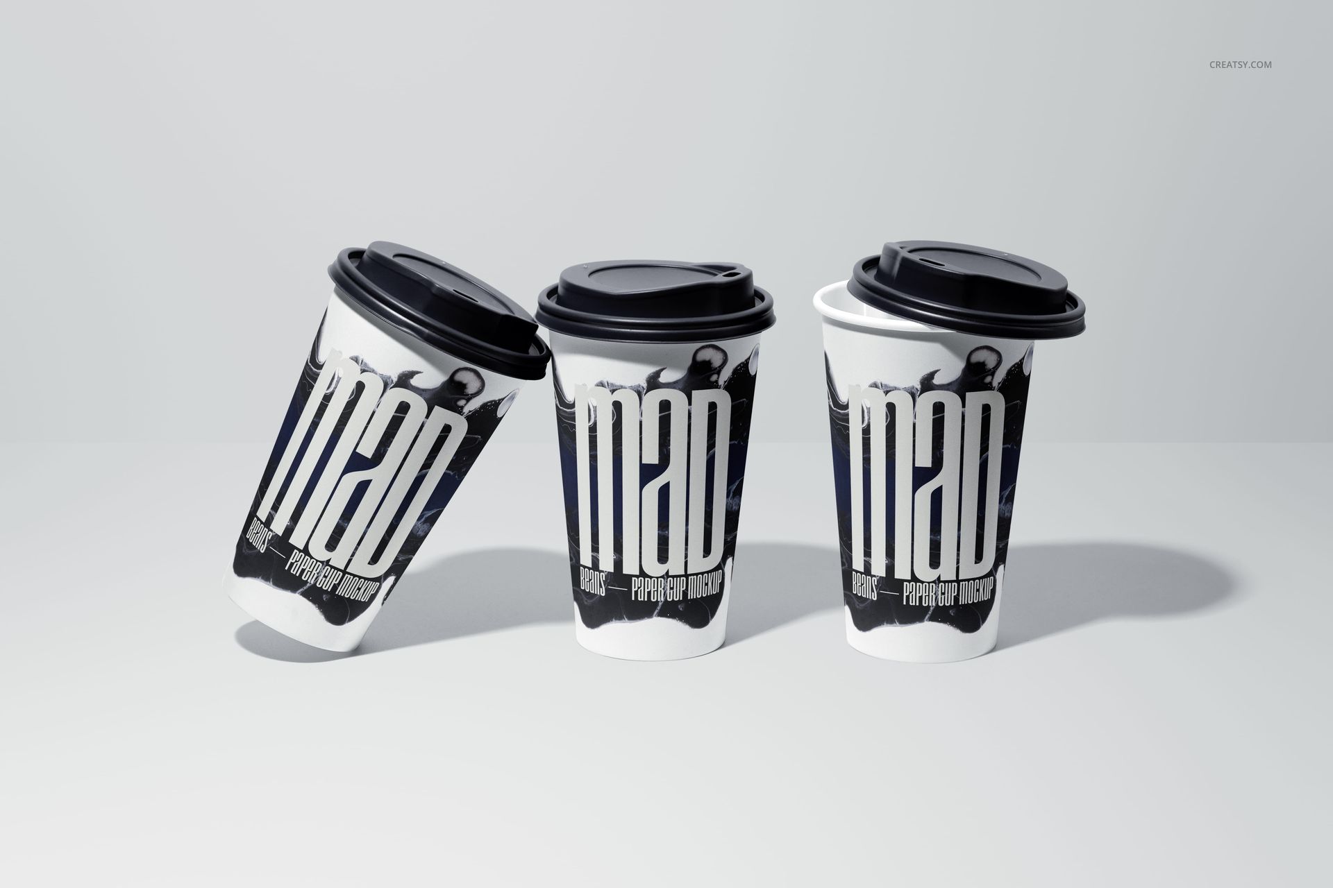 PSD mockup of three paper cups with black lids, arranged on a plain surface, showcasing customizable printed designs.