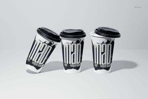 PSD mockup of three paper cups with black lids, arranged on a plain surface, showcasing customizable printed designs.