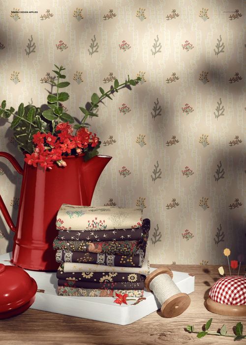 PSD mockup showing folded jersey fabrics with various patterns, accompanied by a red pitcher, spool, and pincushion.