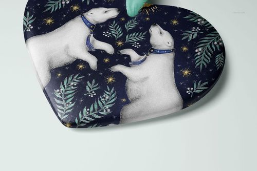 Heart-shaped Christmas ornament mockup featuring a polar bear pattern with green foliage and gold stars on a dark background.