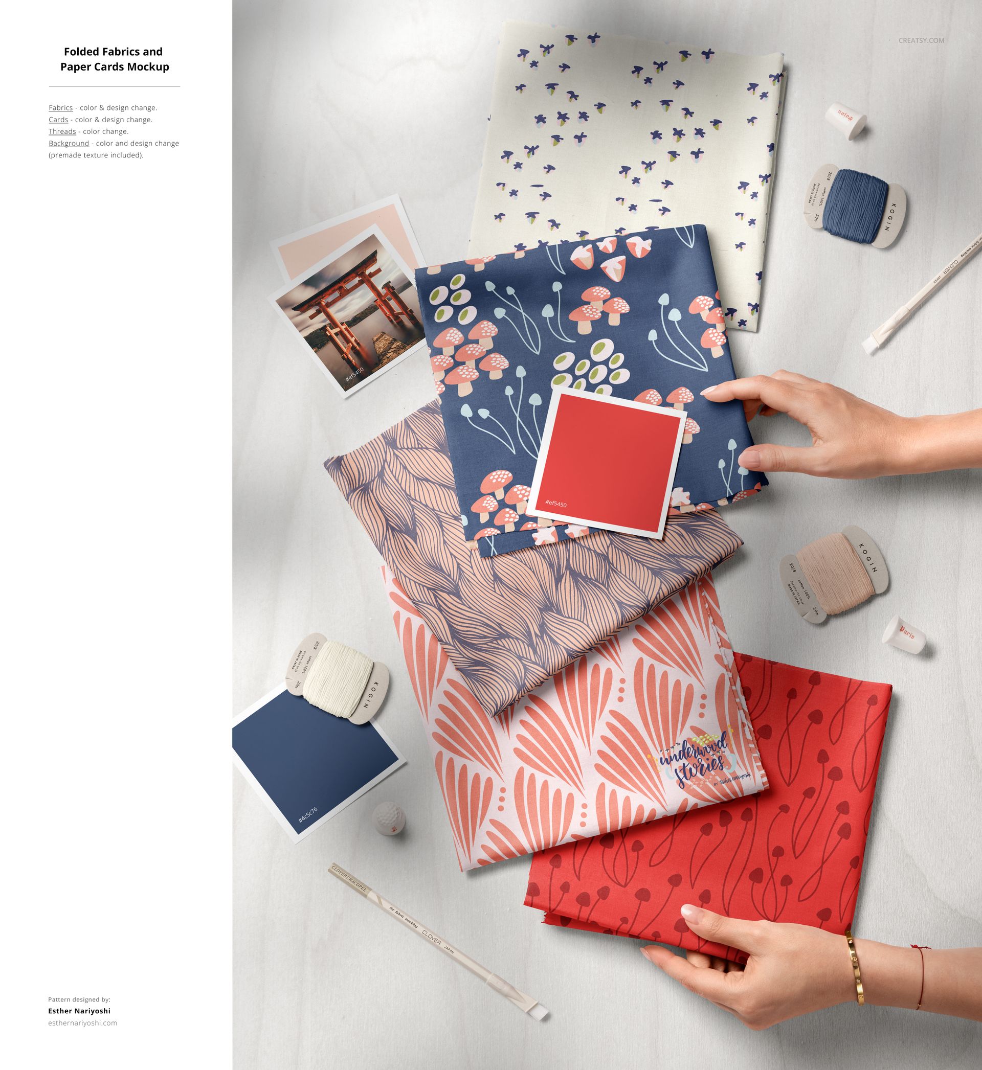 Overhead shot of cotton fabric mockup featuring stacked patterned textiles, thread spools, needles, and paper cards.
