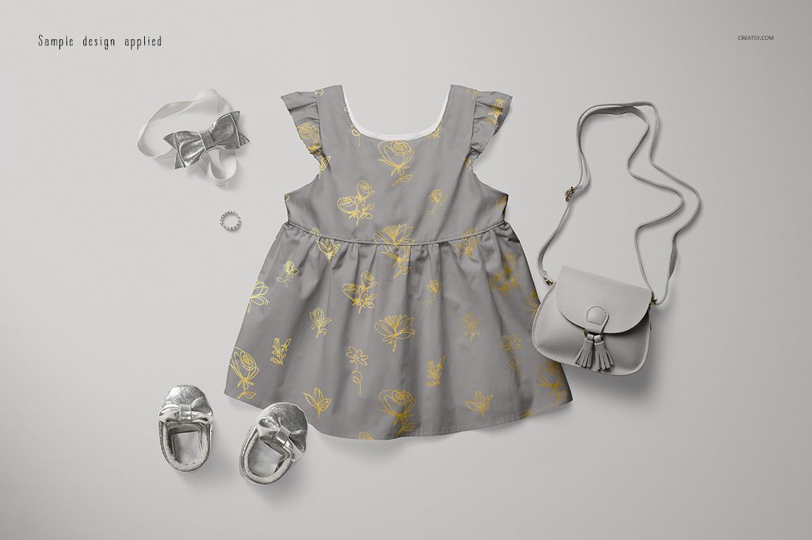 Front view of a gray baby dress mockup with gold floral accents, styled with silver shoes, headband, and purse.