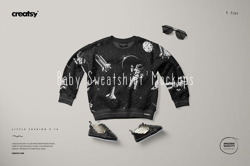 Black baby sweatshirt mockup featuring astronaut and space graphics, laid flat with sneakers and sunglasses nearby.